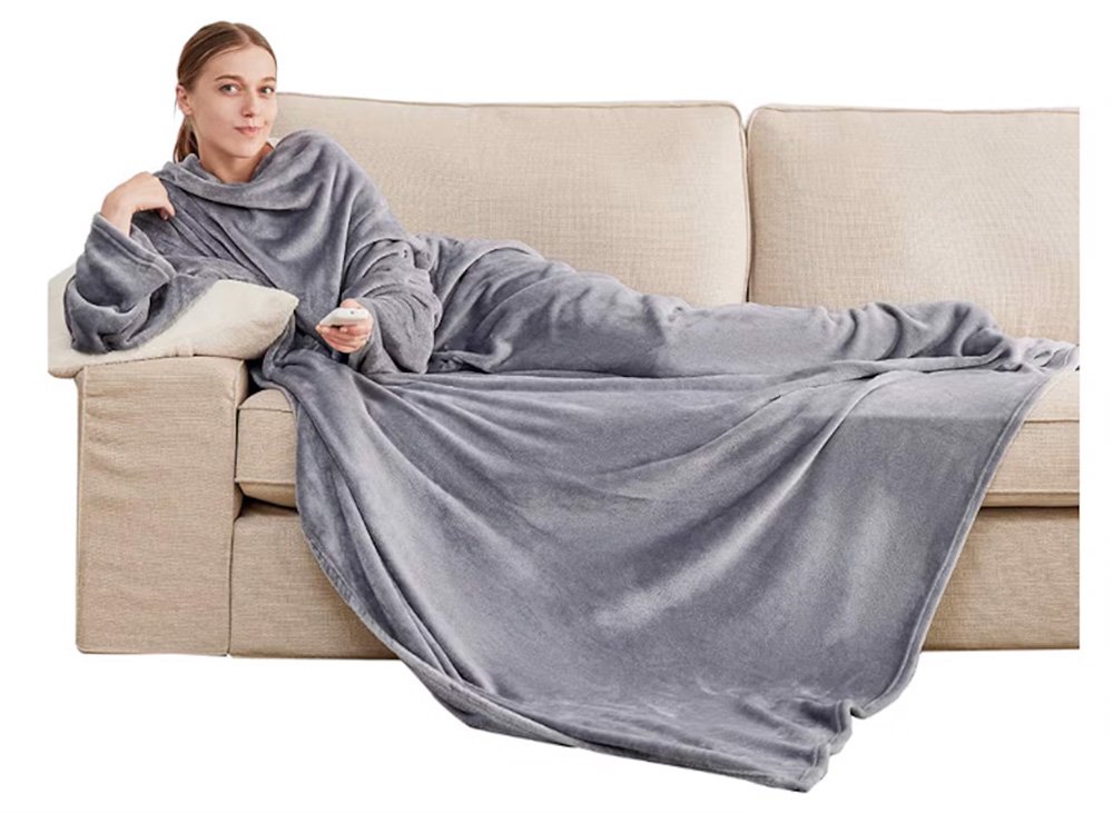 woman sitting on a couch wearing a gray hooded long blanket while clicking a tv remote